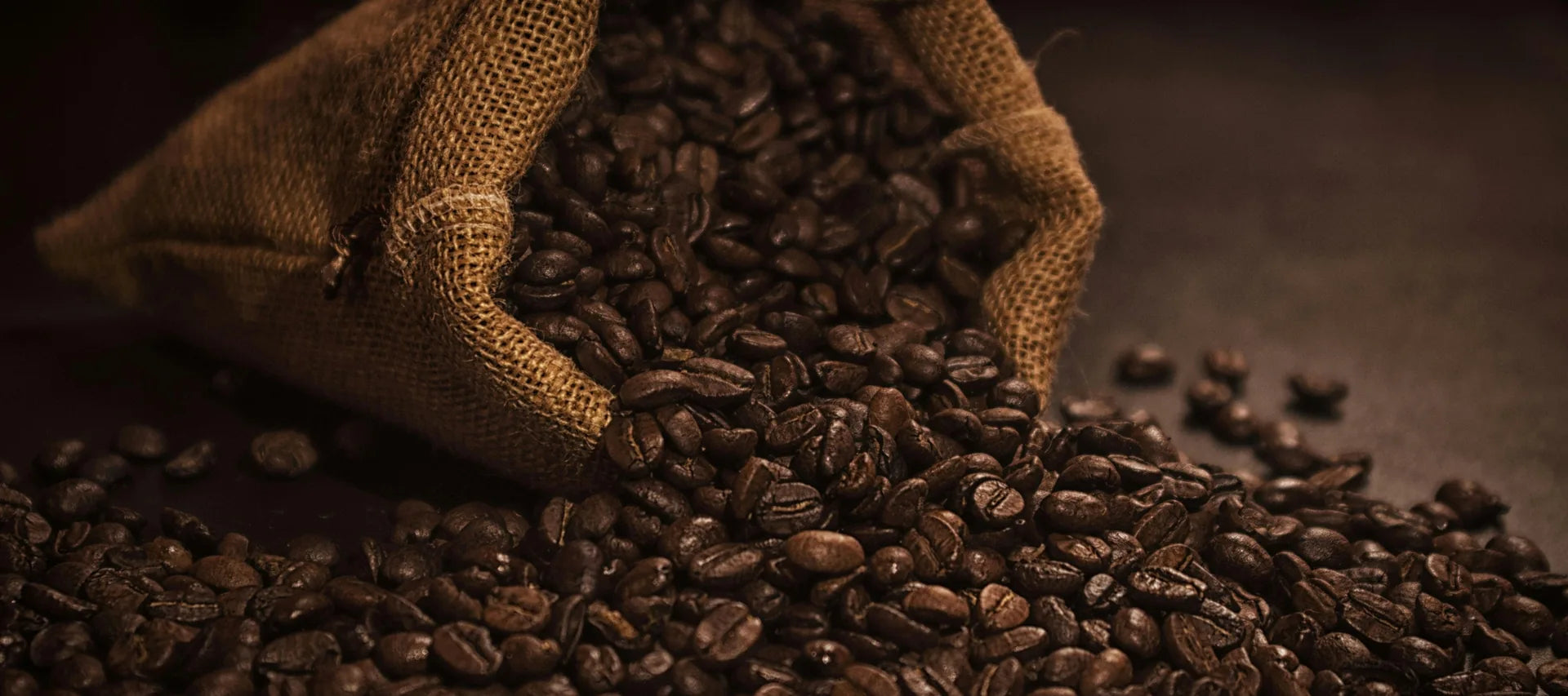 Fresh roasted coffee beans spilling from a burlap sack for Izzy Coffee