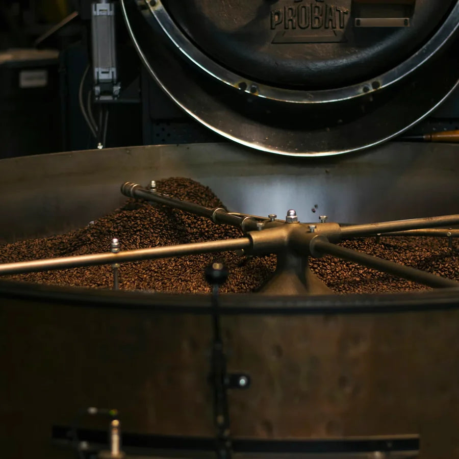 Fresh roasted coffee beans in a roaster for Izzy Coffee
